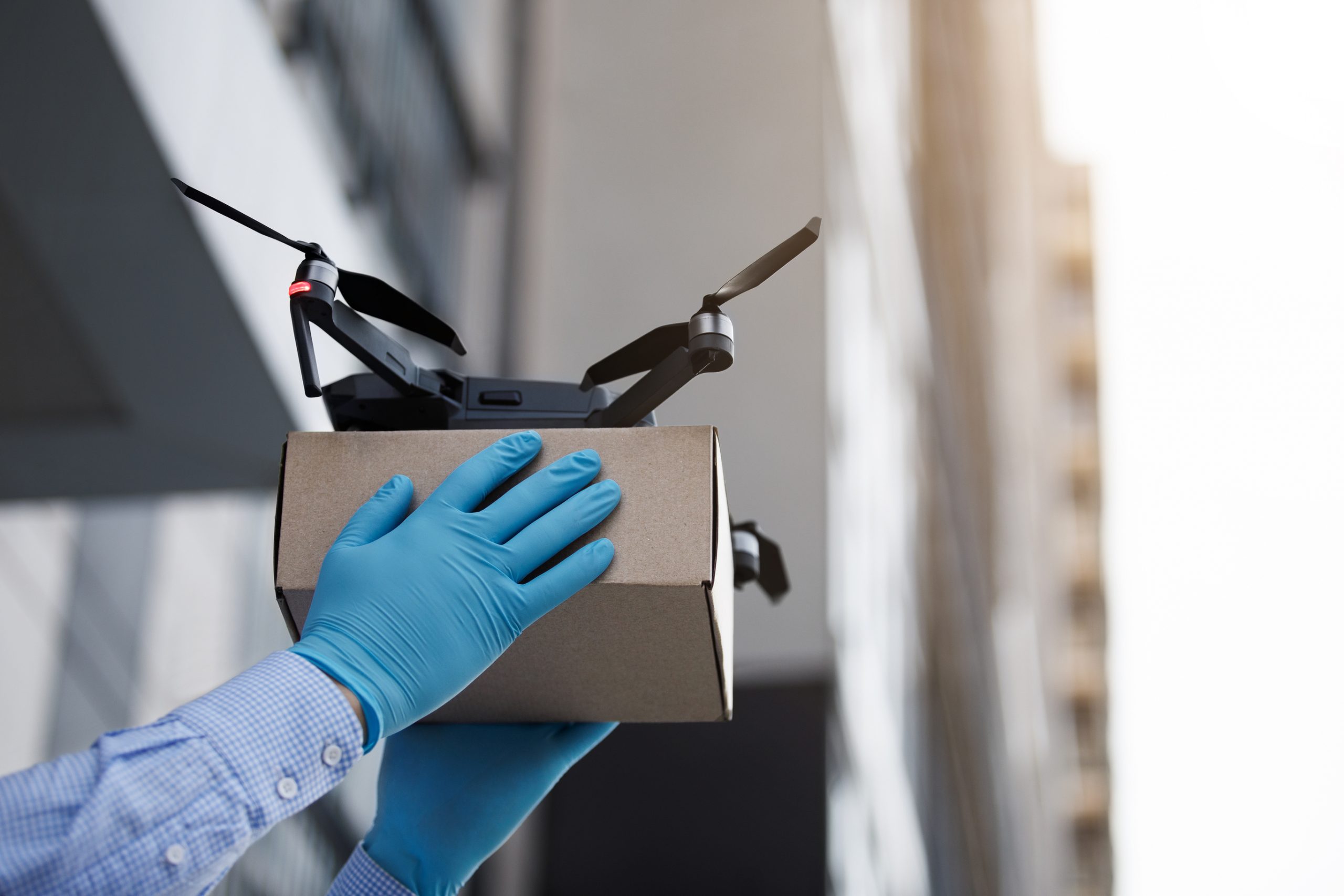 Man wearing blue medical gloves using drone for fast delivery of package